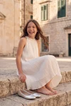 Rochie albă plisată Rozalia în aer liber – fată așezată pe trepte de piatră