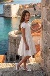 Rochie albă Rumi cu mâneci lalea – în aer liber, lângă un zid de piatră