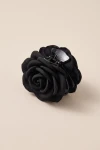 Clamă de păr neagră cu trandafir din material textil, pe fundal bej – unghi de trei sferturi