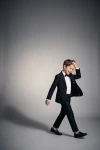 Costum pentru băiat Sam negru cu papion – băiat în mișcare pe fundal gri, sacou descheiat
